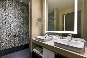Badezimmer im Seven Seas Hotel Life mit zwei Waschbecken, Spiegel und Kacheln.