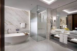 Badezimmer im Atlantis The Royal mit Badewanne, Glasdusche und Waschbecken.