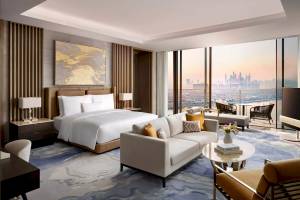 Innenansicht der Suite im Atlantis The Royal Hotel mit Bett, Sofa, Tisch und Aussicht auf die Stadt.