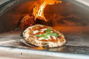 Pizza mit Mozzarella und Basilikum wird aus einem Ofen entnommen