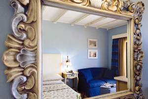 Spiegel im Hotelzimmer von CPH Pevero mit Blick auf ein Bett und ein Sofa