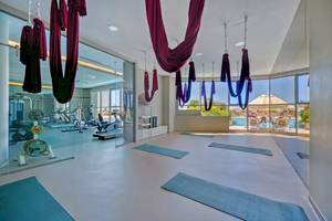Yogaraum im Melas Resort mit Blick auf den Pool und Fitnessgeräten.