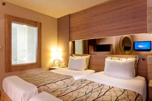 Doppelzimmer im Melas Resort mit zwei Betten, Fernseher und Holzwand