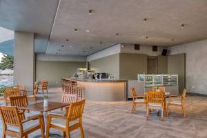 Innenbereich des Melas Resorts Hotels mit Bar und Tischen, umgeben von Holzmöbeln.