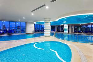 Innenpoolbereich des Melas Resorts mit blauen Wänden und Säulen, gefüllt mit klarem Wasser.