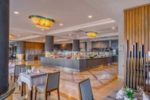Innenansicht des Restaurants im Melas Resort mit Buffet, Tischen und Stühlen.