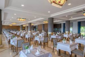 Innenraum des Restaurants im Melas Resort mit vielen gedeckten Tischen und Stühlen.