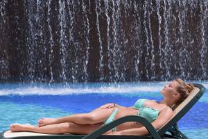 Frau im Pool vor einem Wasserfall am Novum Garden Side Hotel