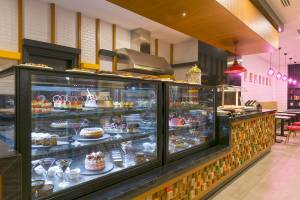 Innenansicht des Cafés im Novum Garden Side Hotel mit Vitrinen voller Kuchen und Desserts.
