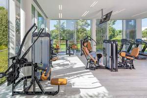 Fitness-Center im Oberoi Beach Resort Al Zorah mit modernen Geräten und einer Frau, die sich entspannt.