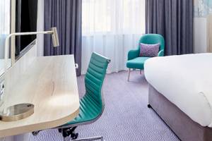 Leonardo Hotel London Croydon Zimmer mit Bett, Schreibtisch und Stühlen.