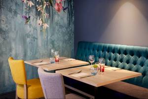 Innenbereich des Leonardo Hotel London Croydon mit zwei Tischen und einer Bank.