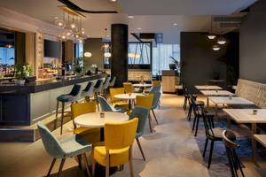 Innenbereich des Leonardo Hotel London Croydon mit Bar, Tischen und Stühlen.