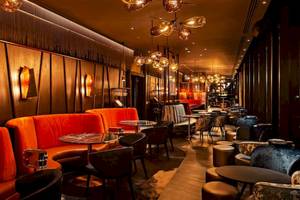 Innenbereich des DoubleTree by Hilton Tower of London mit roten Sofas, Tischen und Kronleuchtern.