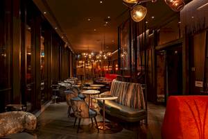Innenansicht des DoubleTree by Hilton Tower of London mit Lounges, Tischen und dekorativen Leuchten.