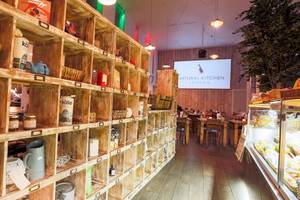 Innenansicht des Natural Kitchen London im DoubleTree by Hilton Tower of London mit Regalen, Tischen und einer Tafel