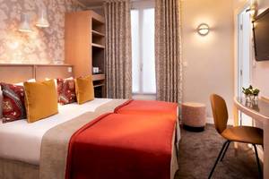 Doppelzimmer im Les Jardins d'Eiffel Hotel mit zwei Betten, farbigen Kissen und einem Schreibtisch.