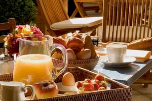 Frühstücksbuffet im Hotel Les Jardins d'Eiffel mit Brot, Croissants, Früchten und Getränken.