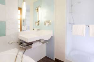 Badezimmer im Novotel Paris Tour Eiffel mit weißer Badewanne und Duschkabine.