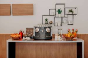 Frühstücksbuffet im Novotel Paris Tour Eiffel mit Kaffeemaschine, Obst und Getränken.