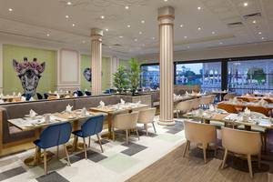 Innenansicht des Restaurants des Titanic Mardan Palace Hotels mit runden Tischen und Stühlen.