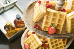 Gebackene Waffeln mit roten Beeren und Honig auf einem Tablett im Novotel Paris Tour Eiffel