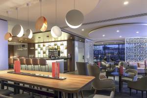 Loungebereich des Novotel Paris Tour Eiffel Hotels mit Bar, Tischen und Stühlen.