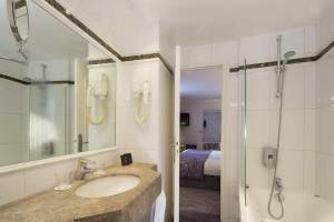 Badezimmer im Victor Hugo Paris Kléber Hotel mit Badewanne, Dusche und Waschbecken.