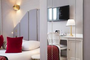 Innenansicht eines eleganten Hotelzimmers im Victor Hugo Paris Kléber mit einem Bett, einem Schreibtisch und einem Fernseher.