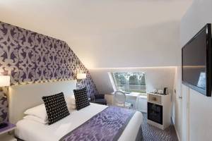 Hotelzimmer im Victor Hugo Paris Kléber mit Bett, Fernseher, Schreibtisch und Fenster