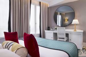 Hotelzimmer im Victor Hugo Paris Kléber mit Bett, Schreibtisch und Spiegel.
