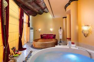 Suite Badezimmer im Titanic Mardan Palace mit Badewanne, Bett und Früchtekorb.
