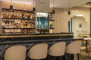 Barbereich des Victor Hugo Paris Kléber Hotels mit Marmortheke und Barhockern.