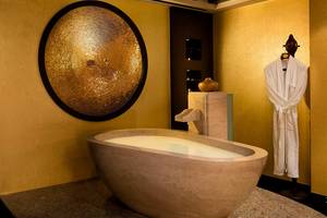 Luxuriöses Badezimmer im Titanic Mardan Palace mit goldener Wand und freistehender Badewanne.