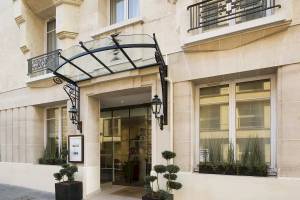 Eingang des Victor Hugo Paris Kléber Hotels mit Glasdach und schwarzen Laternen.