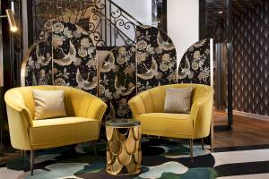 Zwei gelbe Sessel stehen in der Hotellobby von Victor Hugo Paris Kléber neben einem Tisch.