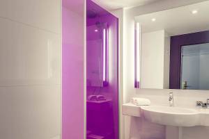 Badezimmer im Mercure Paris Bercy Bibliothèque Hotel mit violetter Dusche und weißem Waschbecken