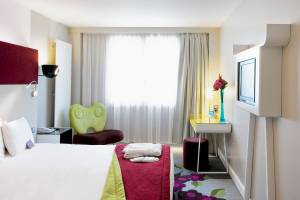 Hotelzimmer im Mercure Paris Bercy Bibliothèque mit Bett, Sessel, Schreibtisch und Fernseher.