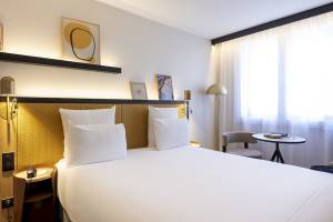 Hotelzimmer im Mercure Paris Bercy Bibliothèque mit einem Bett, weißen Kissen und modernen Dekor.