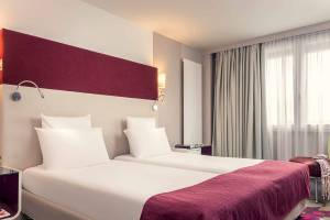 Doppelzimmer im Mercure Paris Bercy Bibliothèque mit zwei Betten und roten Kopfteilen.