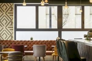 Innenansicht des Restaurants im Mercure Paris Bercy Bibliothèque Hotel mit großen Fenstern und verschiedenen Stühlen.