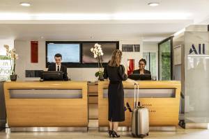 Rezeption im Mercure Paris Centre Tour Eiffel Hotel mit einer Frau, die einen Koffer zieht.