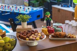 Frühstücksbuffet im ReMIX Hotel mit verschiedenen Desserts, Obst, Getränken und einem Mario-Figuren.