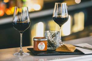 Ein Glas Wein, eine Dose Creme und Cracker auf einem Tisch im ReMIX Hotel.