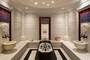 Innenansicht des Spa-Bereichs im Titanic Mardan Palace mit weißen Wänden, schwarzen und weißen Bodenfliesen und dekorativen Elementen.