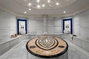 Innenansicht der Sauna im Titanic Mardan Palace mit weißen Wänden, einer zentralen Marmorplatte und Sternen an der Decke.