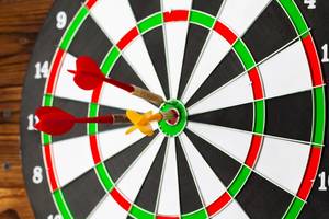 Nahaufnahme einer Dartscheibe mit zwei Pfeilen, die in der Mitte eingesteckt sind.