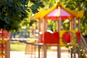 Foto eines bunten Kinderspielplatzes im Freien mit Bäumen im Hintergrund.