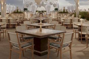 Außenbereich des Sunrise Queen Luxury Hotel mit vielen Tischen und Stühlen, umgeben von weißen Säulen und Brunnen.