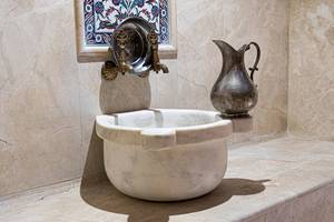 Ein Badezimmer mit einem Marmorwaschbecken und einer alten Kruecke an der Wand.